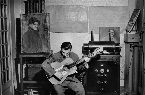 Inge Morath, Pablín, nephew of Picasso, strums guitar next to a portrait of his uncle painted by Picasso's great friend, Sebastià Junyer, Barcelona, Spain , 1954 © Inge Morath / Magnum Photos