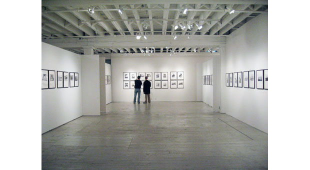 Two people view Landscapes without Memory photographs by Joan Fontcuberta and Parallel Memories photographs by Bruno Rosier on view at Aperture Gallery