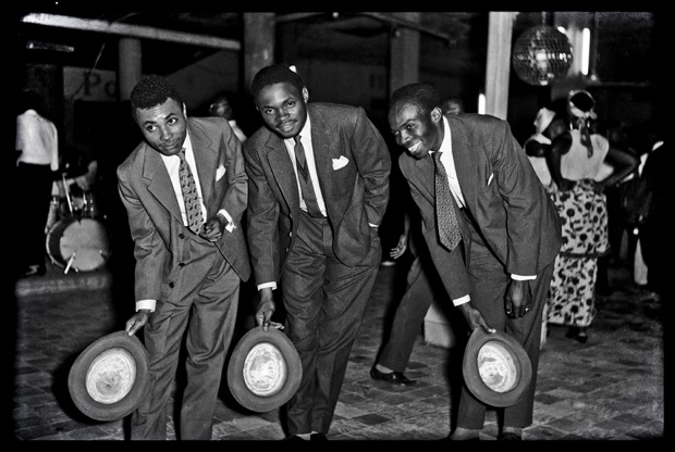 Night in Kinshasa, 1951-1975 Three musicians’ hat salutation; black and white photograph