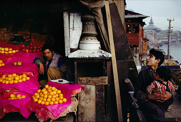 Raghubir Singh, Fruit Seller and a Boy with a Child at Zaina Kadal Bridge, Jhelum River, Srinagar, Kashmir, 1979 © Succession Raghubir Singh 