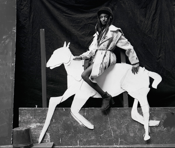 Black-and-white photograph of a person wearing a coat and riding a paper horse