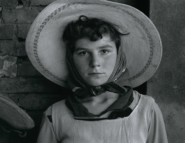 Paul Strand, Worker at the Co-op, Luzzara, Italy, 1953. Portrait of a child wearing a scarf around his head with a straw hat on top.