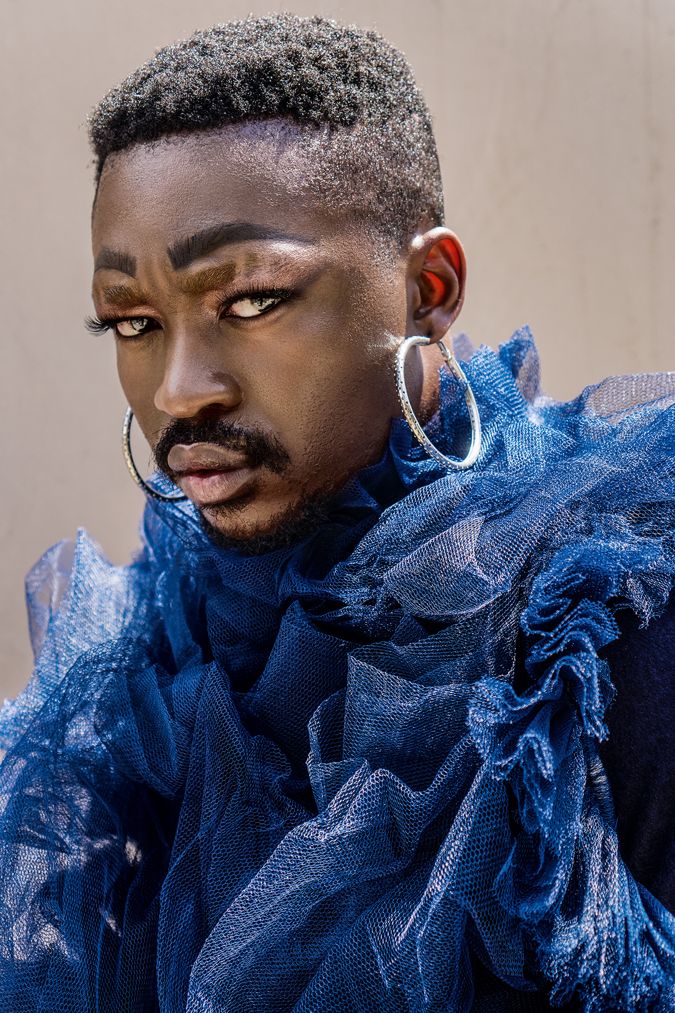 Jamal Nxedlana, FAKA Portrait, Johannesburg, 2019. Portrait of a person with a second set of eyebrows drawn on wearing tulle and hoop earrings.