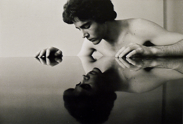 Duane Michals, Narcissus, 1974. A handsome young man looks at his mirror image on a reflective table.