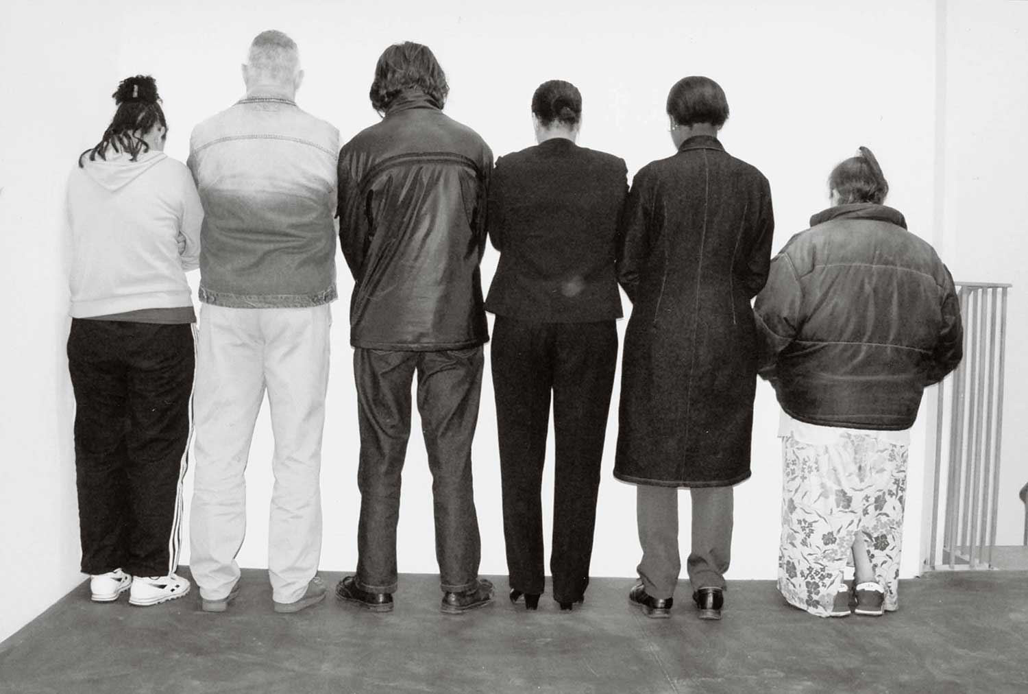 Santiago Sierra, Group of people facing a wall, 2002