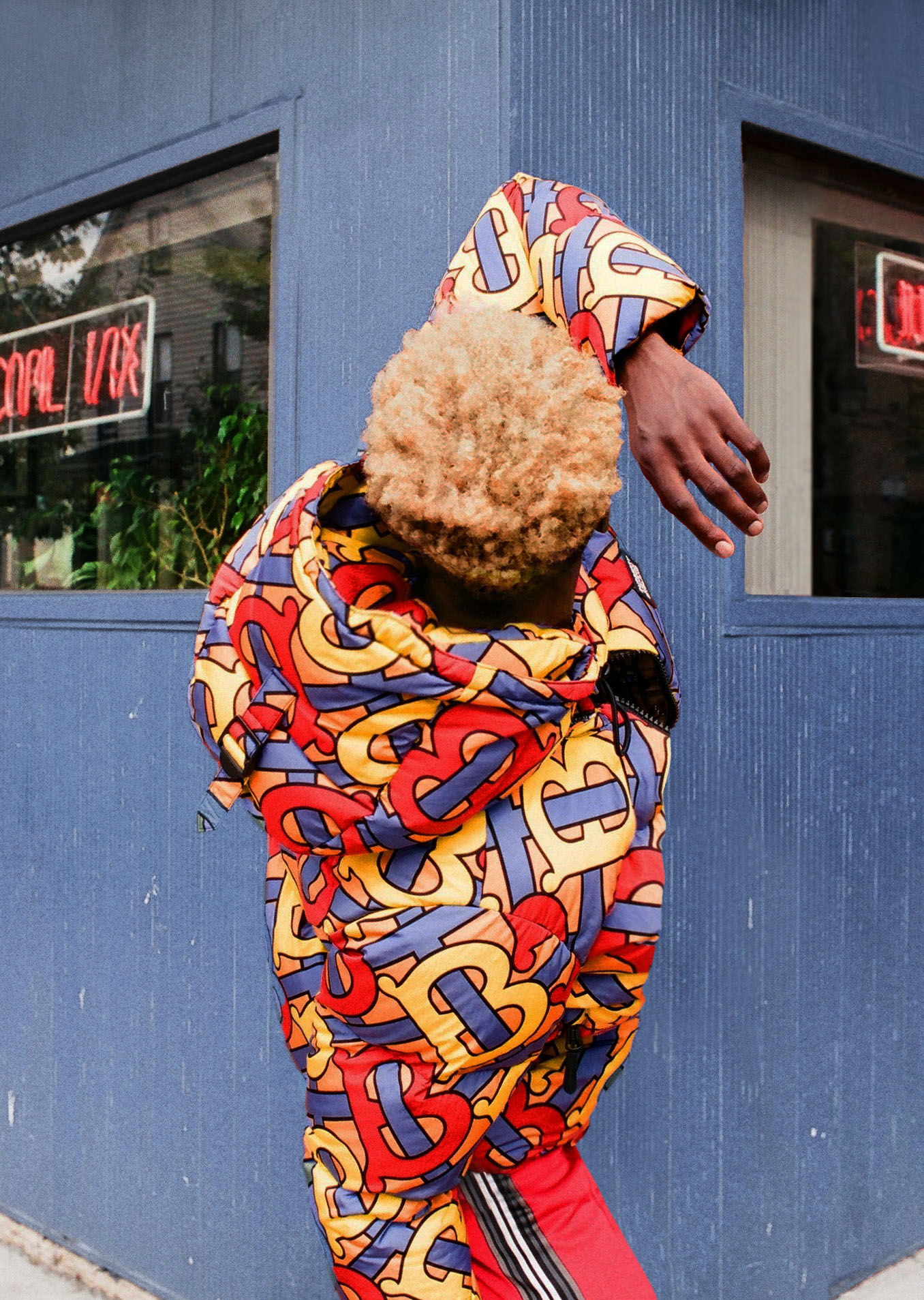 person in puffer jacket against blue building 