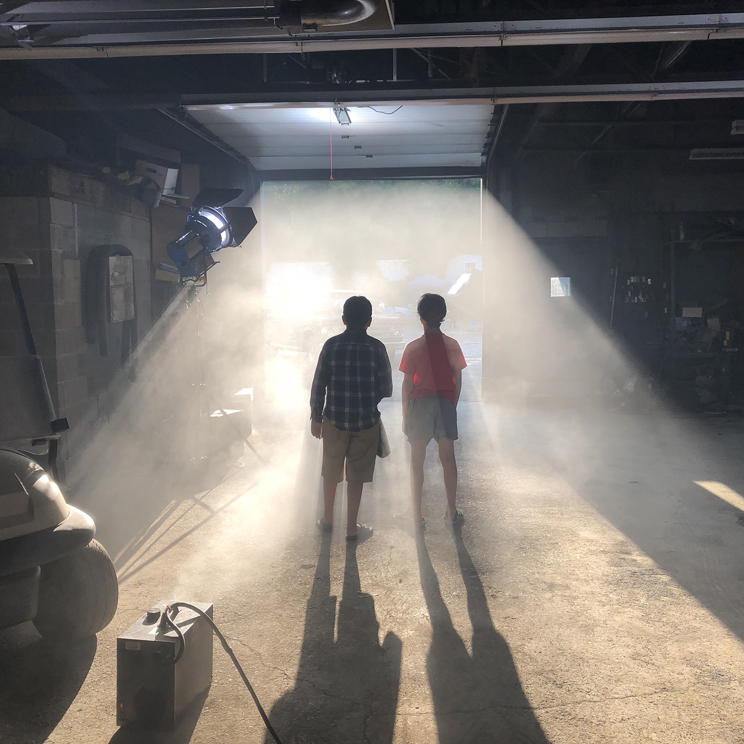 Color photograph of two children with backs turned facing a stream of light