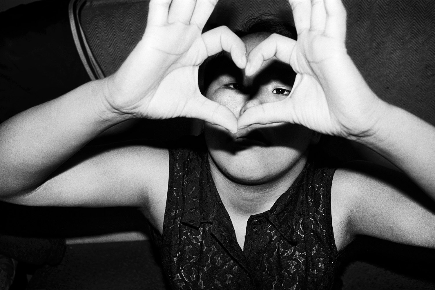 Black and white photograph of figure with hands in shape of heart