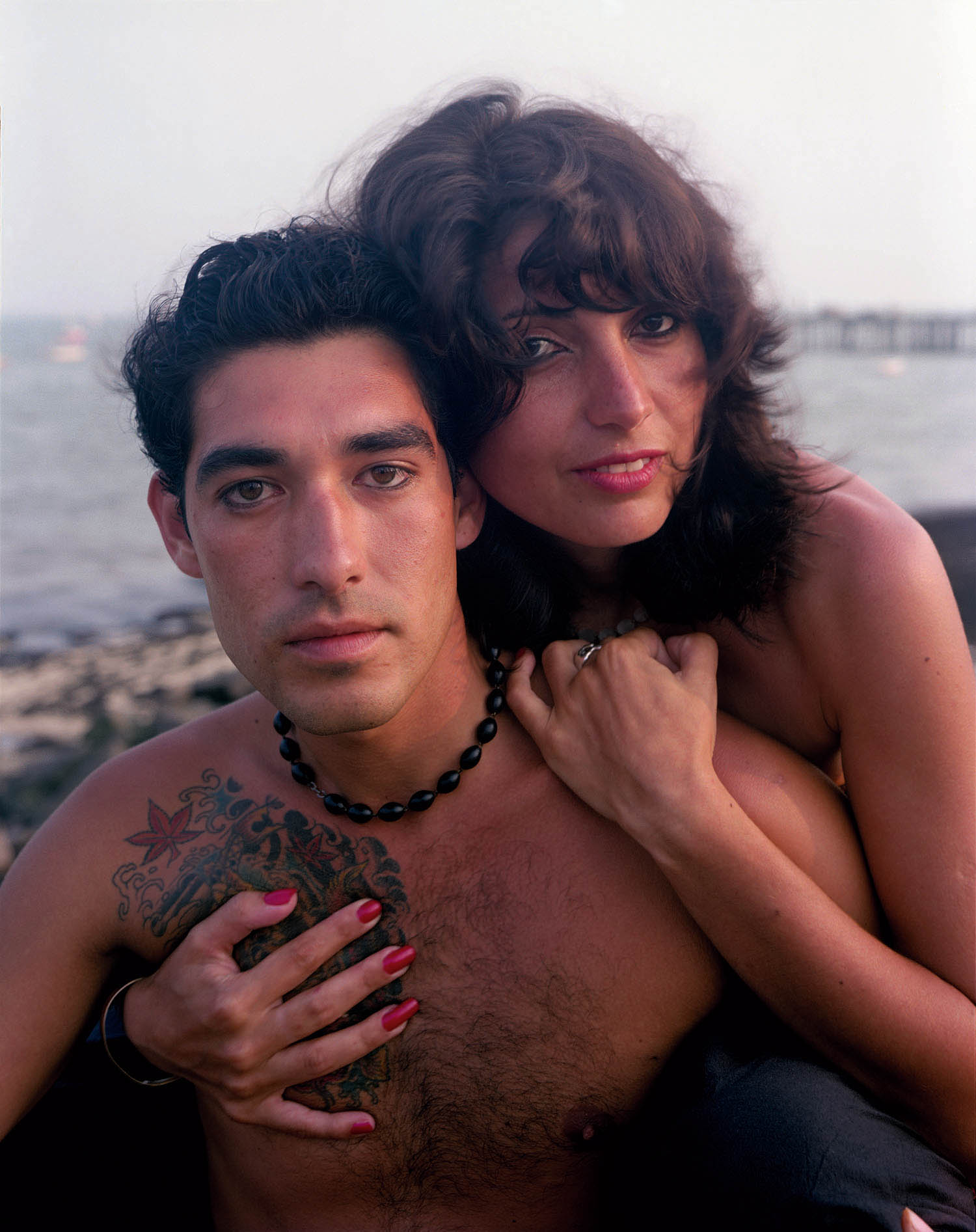 A couple holds each other in front of an ocean landscape