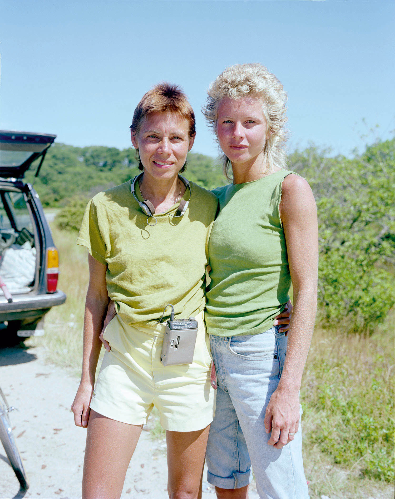 a couple wearing green stands in front of a caar