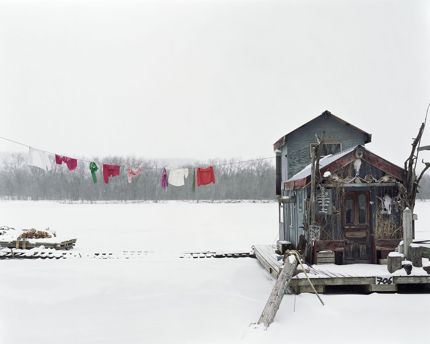 A houseboat on a snowy landscape, with a multi-colored clothing hanging from a clothesline