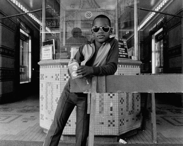 Dawoud Bey, A Boy in Front of the Loew’s 125th Street Movie Theatre, Harlem, 1976