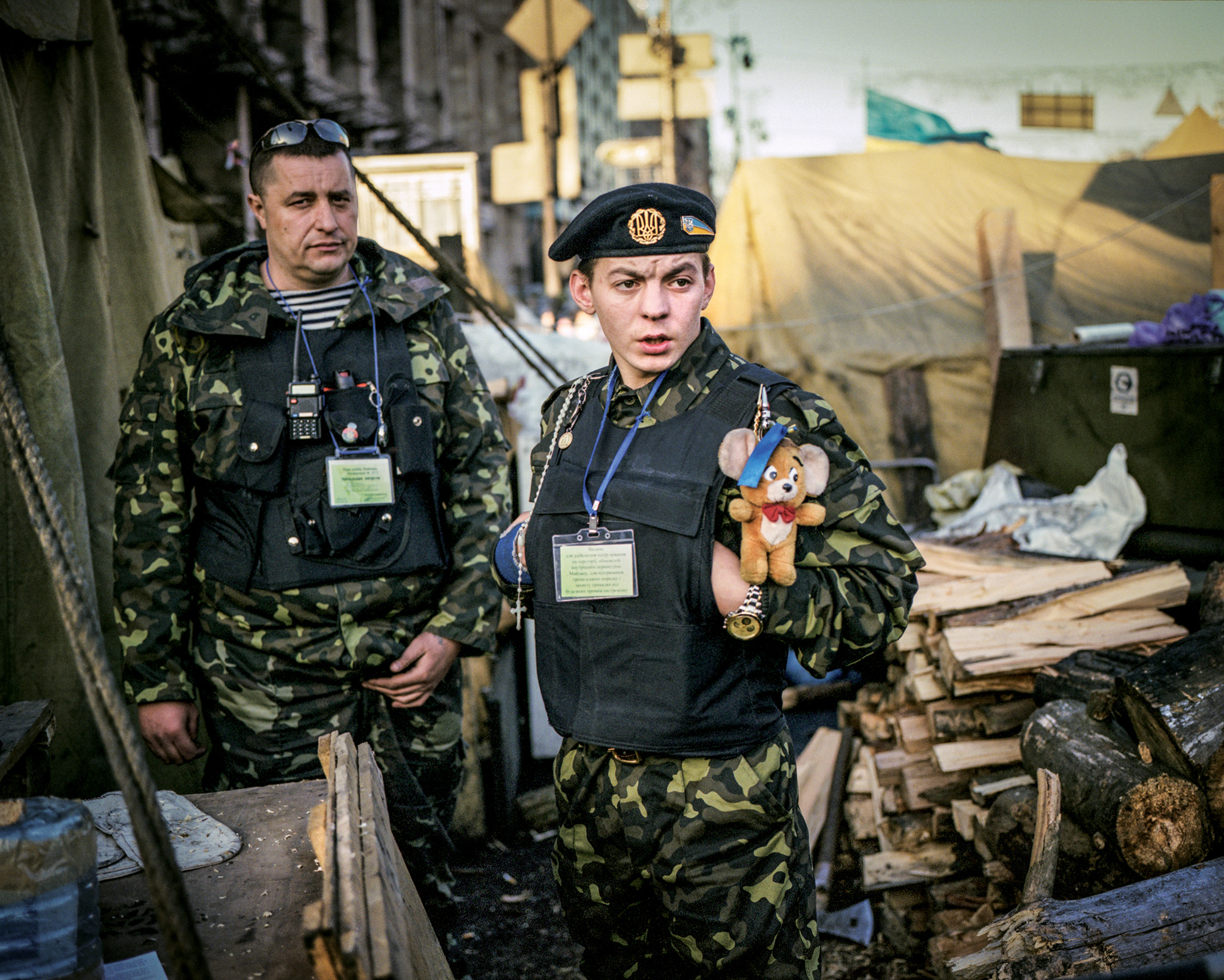 Petro Mironiuk  , March 2014, Kyiv, Ukraine. 

Petro (22) was a volunteer of the protesters self-defense which formed in later weeks of protests  . He came from Carpathian region in Western Ukraine after police brutally beat up protesting students in capitol .  From the Book :
“War changed me. I grew up, as they say,” Petro
 
Petro was a former construction laborer in his early twenties. He came to Kyiv from the Zakarpattia Oblast after seeing how police had beaten the students. He was there when government forces opened fire at the end of February, killing many people. He had been given a teddy bear for luck from a girl who had come to Independence Square. When separatists seized the Donbas region, Petro signed up for the Aidar Battalion as a volunteer and went to fight.

About a year later, I found him in Kyiv hobbling on crutches from wounds sustained in the battle for Luhansk Airport. He had been hanging out aimlessly with other combatants unable to return to the frontlines but not ready to return to their homes. Petro had spent half the year in Luhansk fighting alongside Dima, his friend from Maidan. When they were hit by an artillery blast, Dima was identified only by the red sport shoes he was wearing.
 
“I do not wish that brother kills brother, that he takes up a knife, machine gun, or pistol. That is wrong, I think.” Petro was leaning on crutches in the underground at Kyiv’s Independence Square, awaiting his turn in line for the army hospital to have shrapnel removed from his hands and knee. But he was continually giving up his spot to more heavily wounded casualties brought from the front. Petro was visibly worn out from lack of sleep and was drinking with other ghost-like characters.

“I do not feel joy,” he said. “I am in the middle, as they say. Neither sad nor happy. Just in the middle.” He promised me that he would stop drinking and he finally went to the hospital. He got treatment for his hands but the shrapnel in his knee would ha