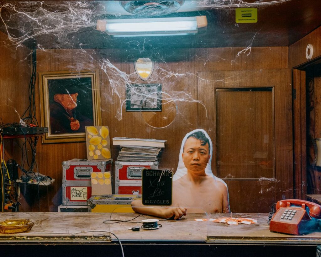 tommy-kha-splendid-memphis A cardboard cutout of an Asian man behind in box office behind a clear partition.