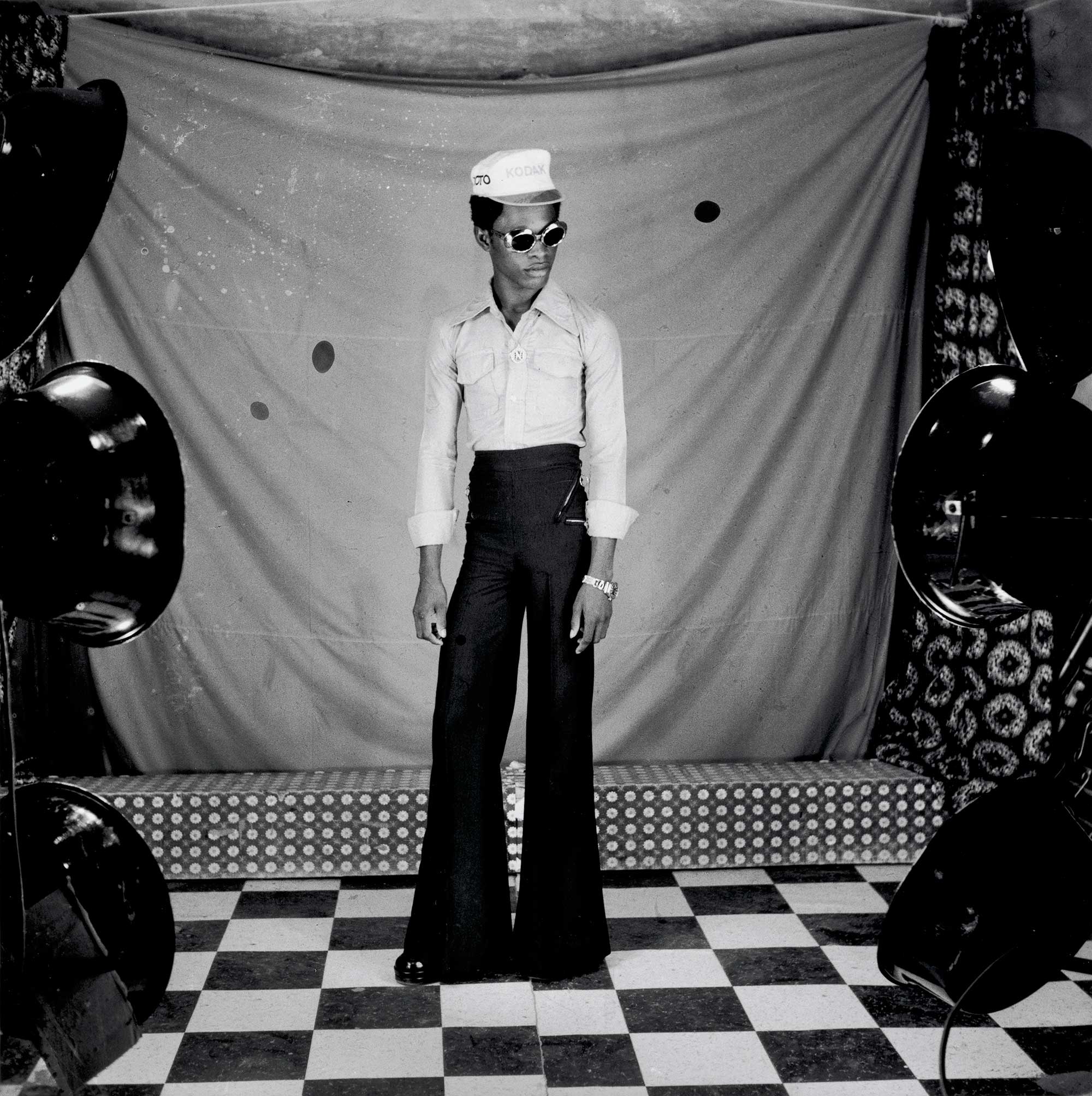 Black and white portrait of a young black man in bellbottoms and sunglasses