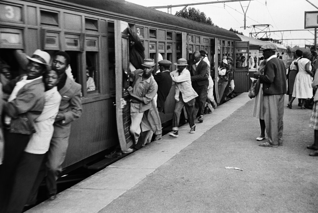 People lean out an overcrowded train.