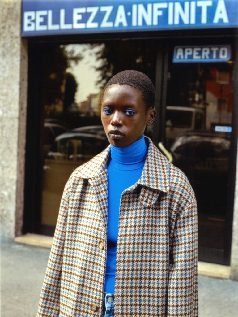 Color photograph of a black woman in a blue and brown patterned coat