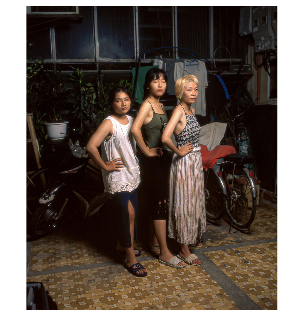 Three women standing together in a room, looking at the camera.