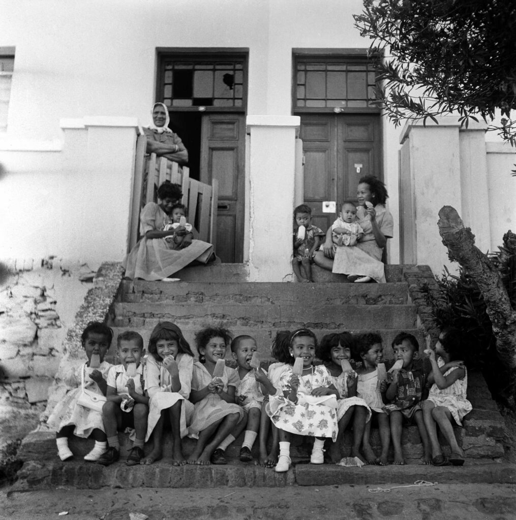 Black and white photograph of children sitting on steps in Cape Town