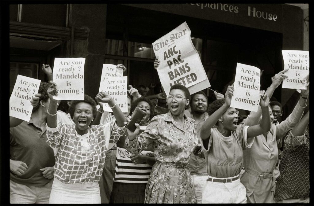 Black and white photograph of South African women holding posters about the un-banning of the ANC