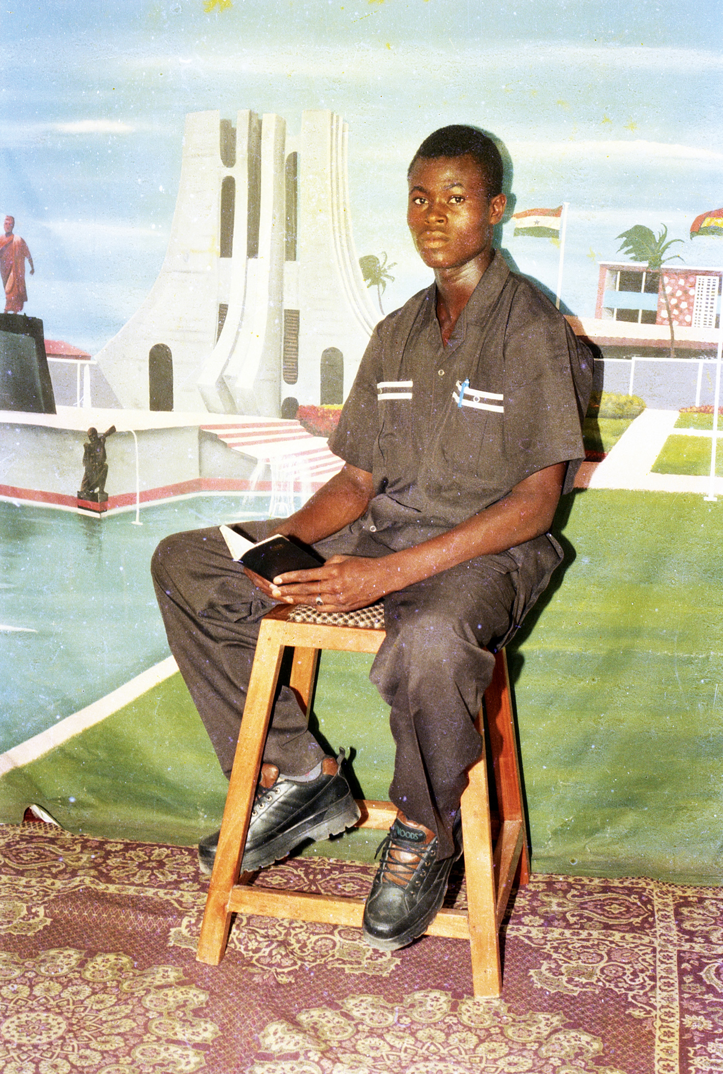 Asante “Obra Photo” Joseph, Young man photographed in studio with a backdrop of Kwame Nkrumah Memorial Park
&amp; Mausoleum, ca. 1990s<br>© and courtesy the artist and Saman Archive