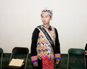 A young boy wearing a crown and a sash that reads "Prince Charming 2015."