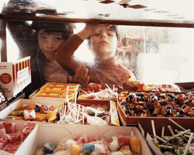 Two young children peer into a candy case.