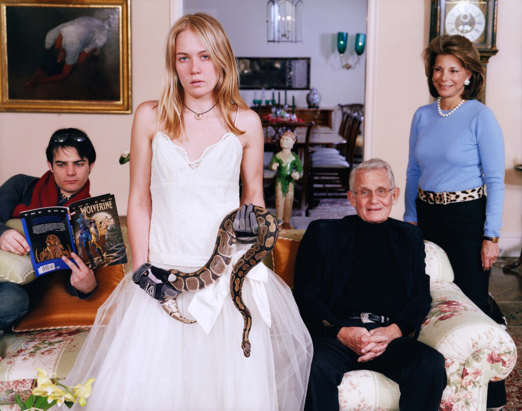 Family Commisson With Snake (Close Up), 2007 A young girl in a white dress holds a large snake in a living room. Three familial individuals are behind her.