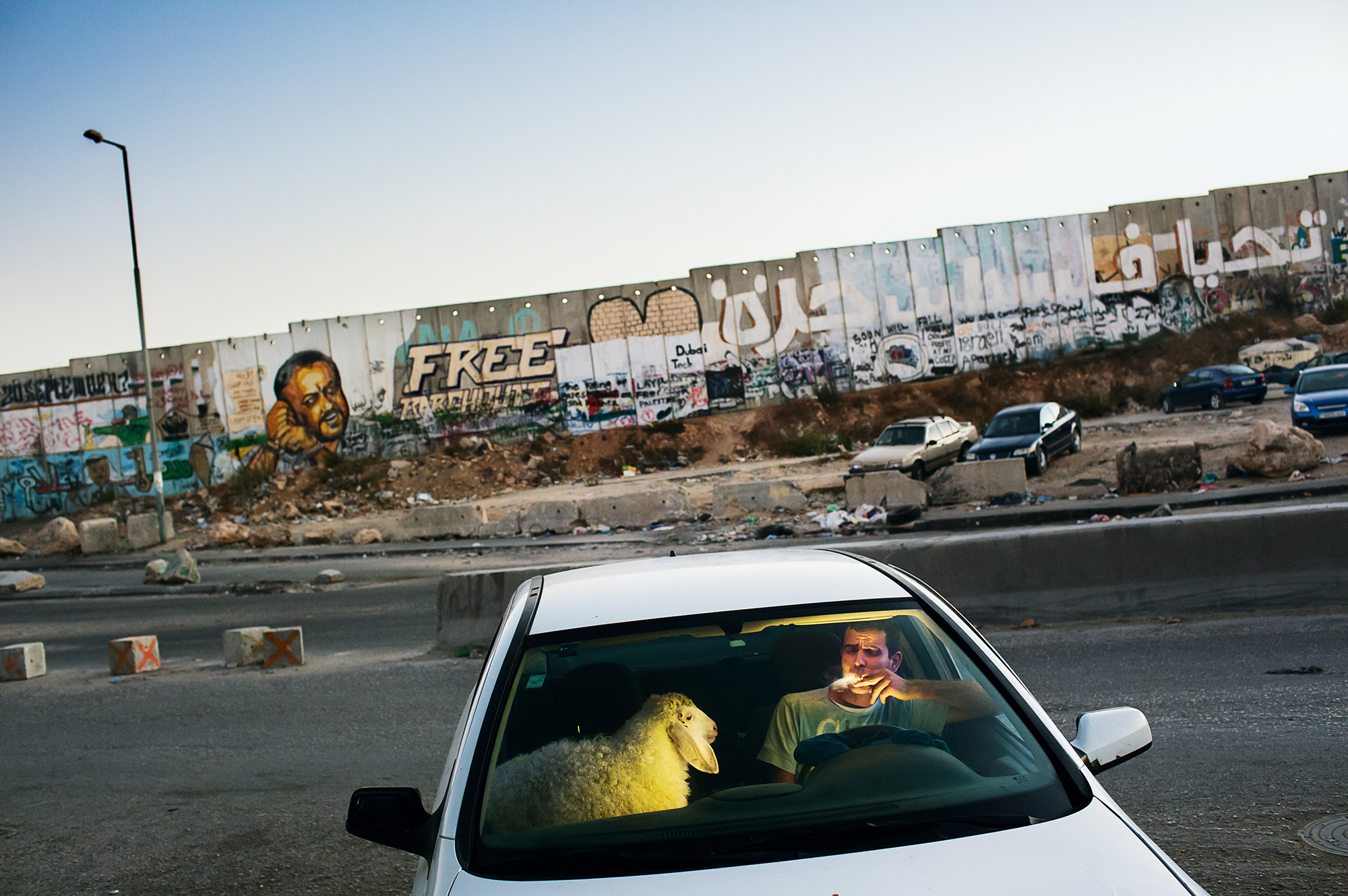  Tanya Habjouqa, Occupied Palestinian Territories, West Bank, Qalandia, 2013. After grueling traffic at the Qalandia checkpoint, a young man enjoys a cigarette in his car as traffic finally clears on the last evening of Ramadan. He is bringing home a sheep for the upcoming Eid celebration.
Courtesy Noor Images 