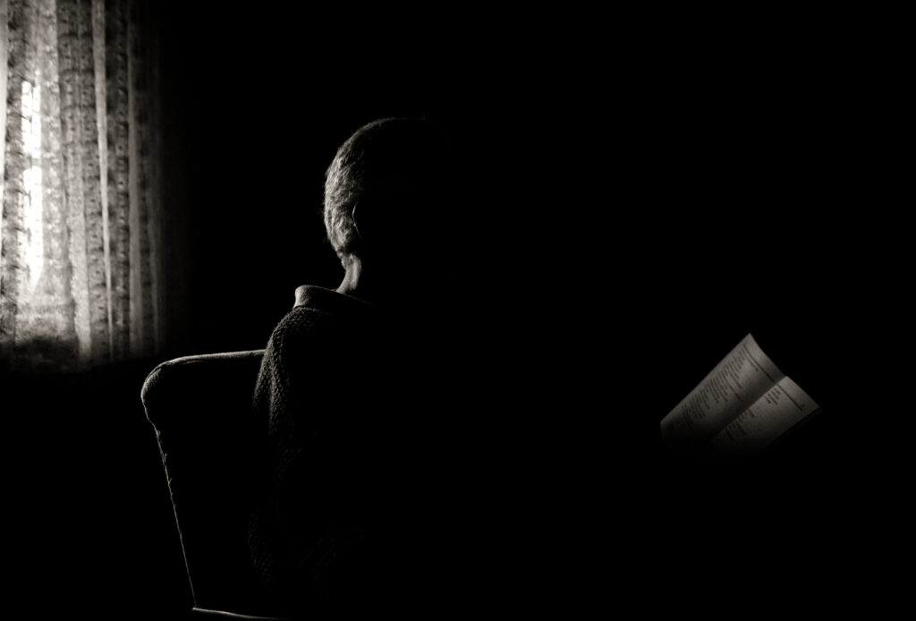 An older gentleman sits and reads.