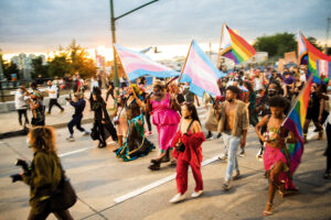Individuals flood a street carrying LGBTQ-related flags.