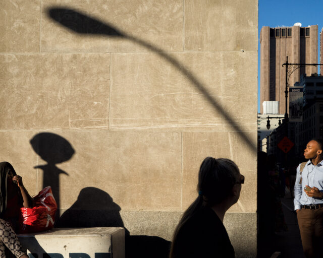 Shadows people on a wall on a city street.