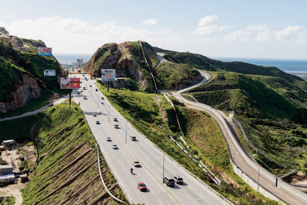 An aerial photograph of a freeway bisecting lush green hills.