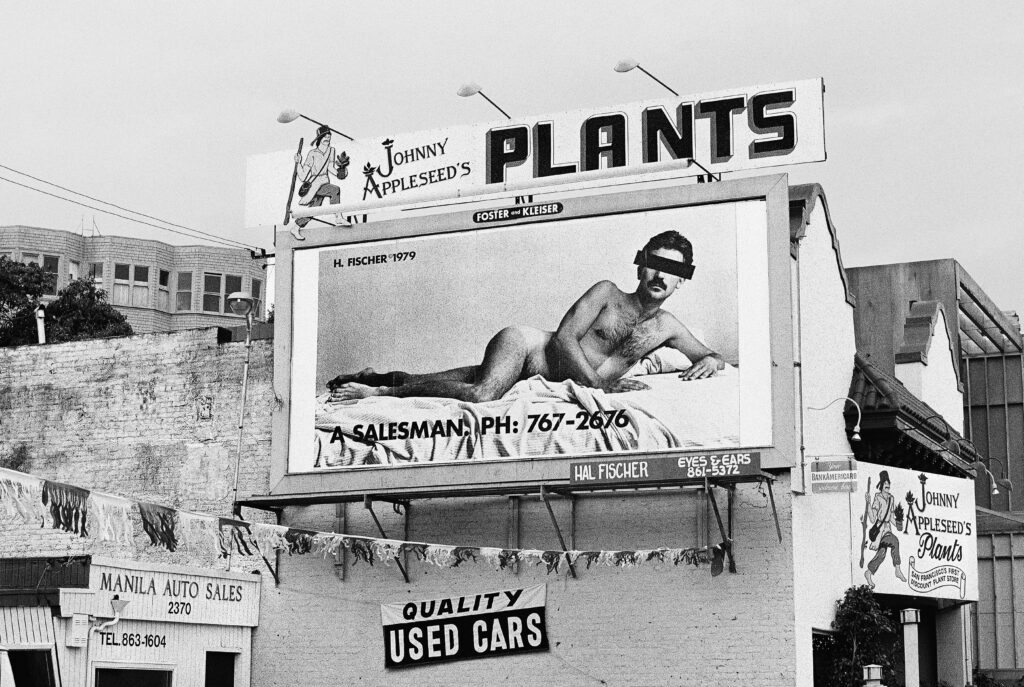 A billboard featuring a nude man reclining on a bed.